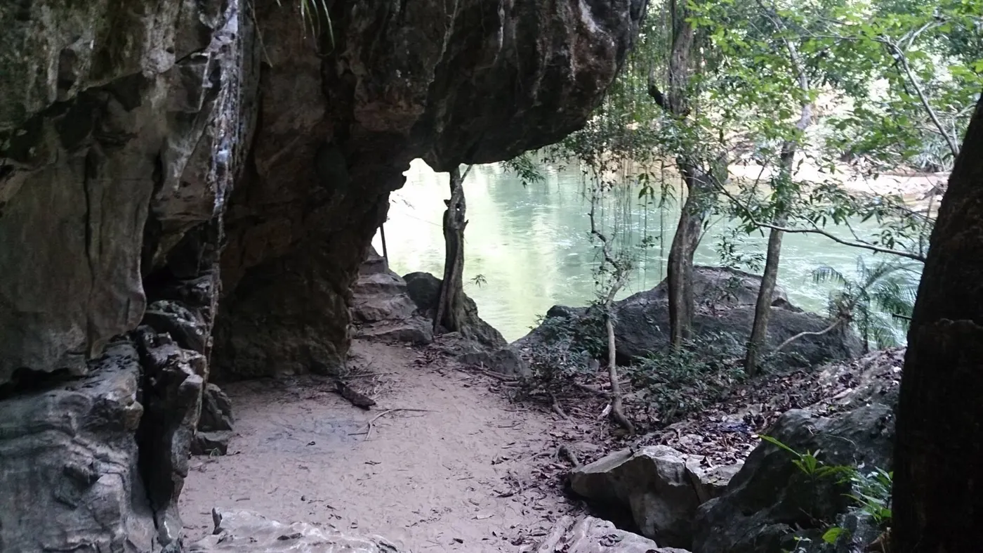 Sendero bajo una pared de roca junto al agua en la Reserva Natural Río Claro